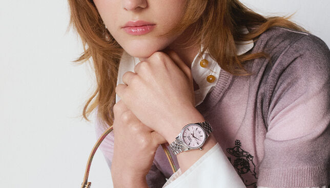 Woman wearing a silver Vivienne Westwood watch and tartan dress, with the Vivienne Westwood Time Machine logo in the background